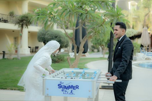 A bride and groom enjoy a game of foosball outside during their wedding celebration.
