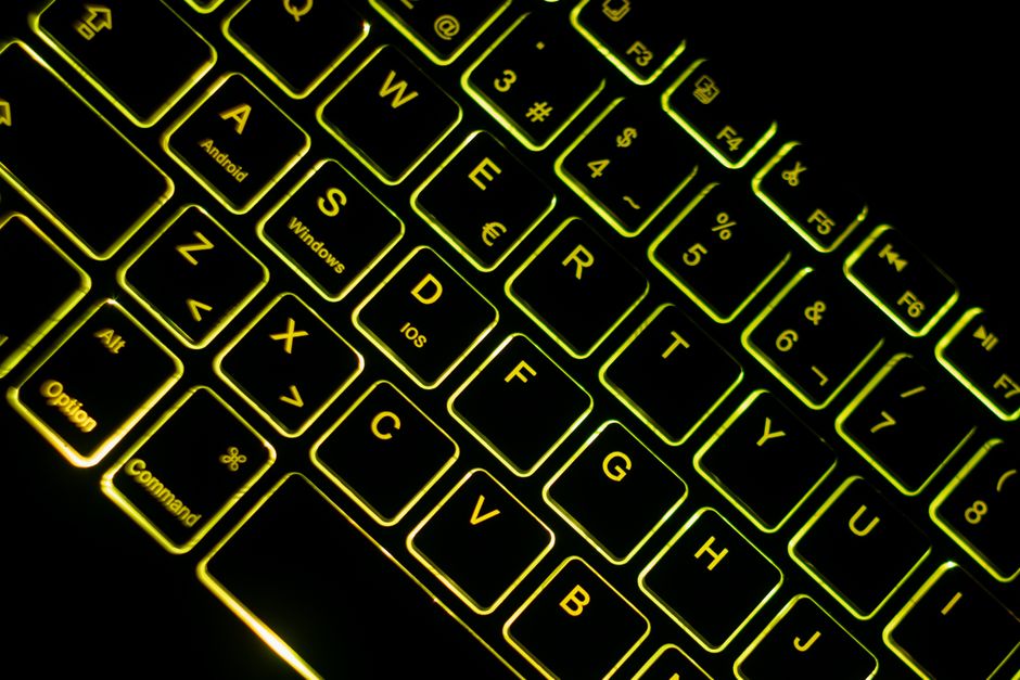 Fotomural Primer plano de un teclado retroiluminado neón en un entorno oscuro, con un brillo verde-amarelado vívido.