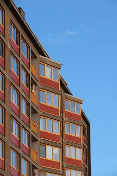 Tall apartment building with colorful facade set against a clear blue sky, showcasing urban architecture.