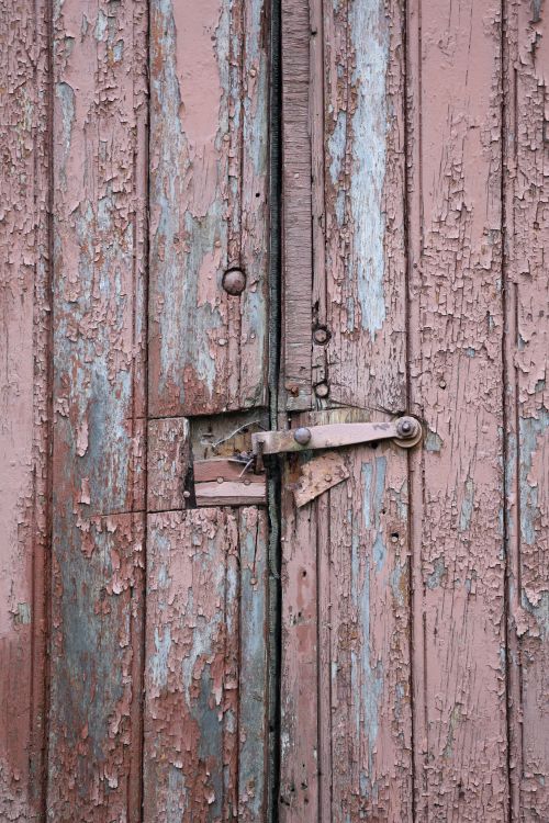 Free Close-up of an old door with peeling pink and blue paint showing decay and texture. Stock Photo