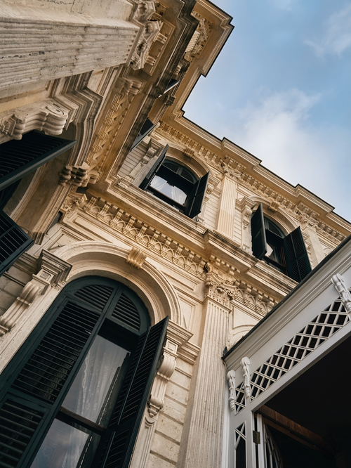 Free Upward view of a historic building facade with open shutters, showcasing elegant architectural details. Stock Photo