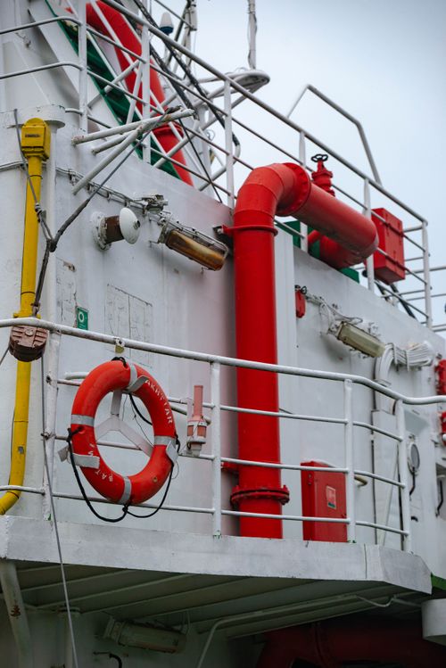 Free Detailed view of a ship's side with bright red life-saving equipment and safety features. Stock Photo