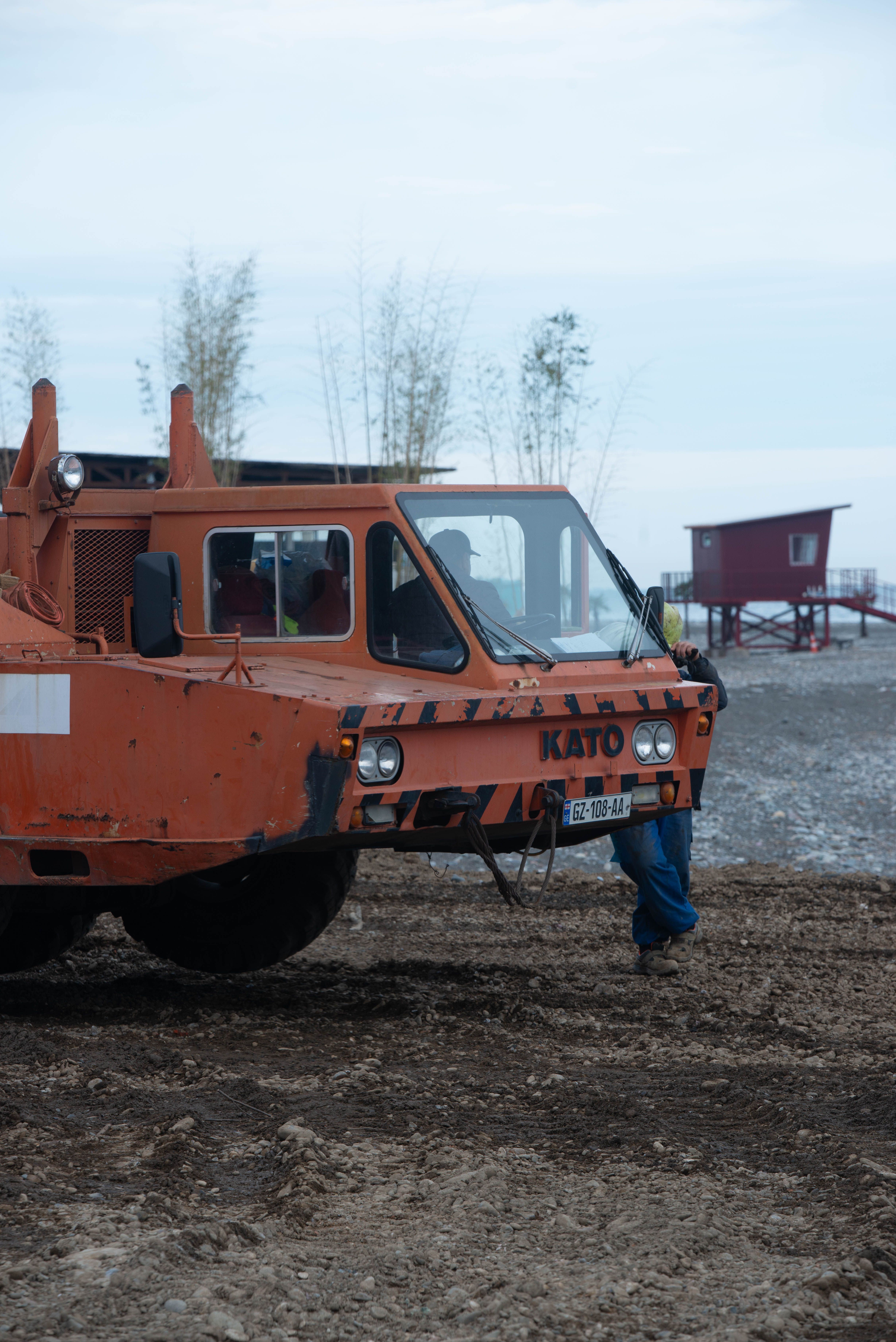Orange KATO construction vehicle at a beachside site with person in view.