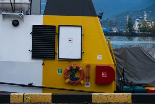 Free Detailed side view of a ship's deck featuring safety equipment and harbor background. Stock Photo