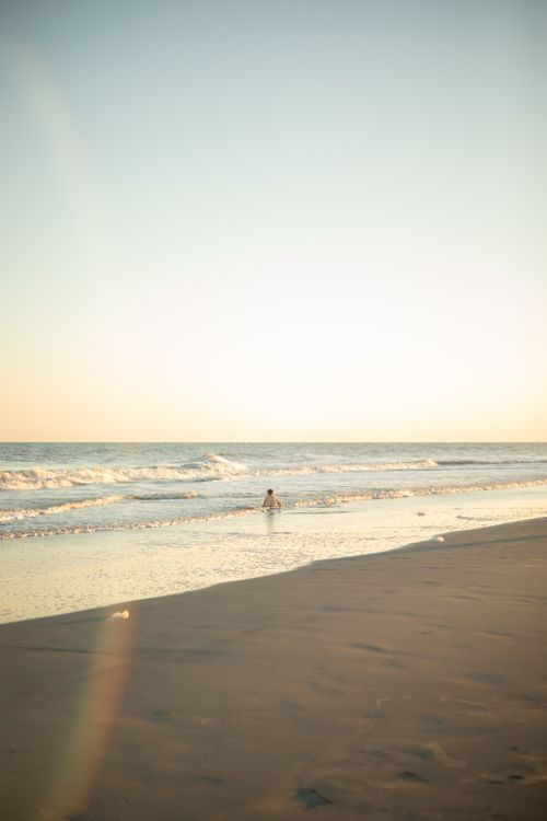 Free A child enjoys a summer day playing in the waves at Folly Beach, SC during sunset. Stock Photo