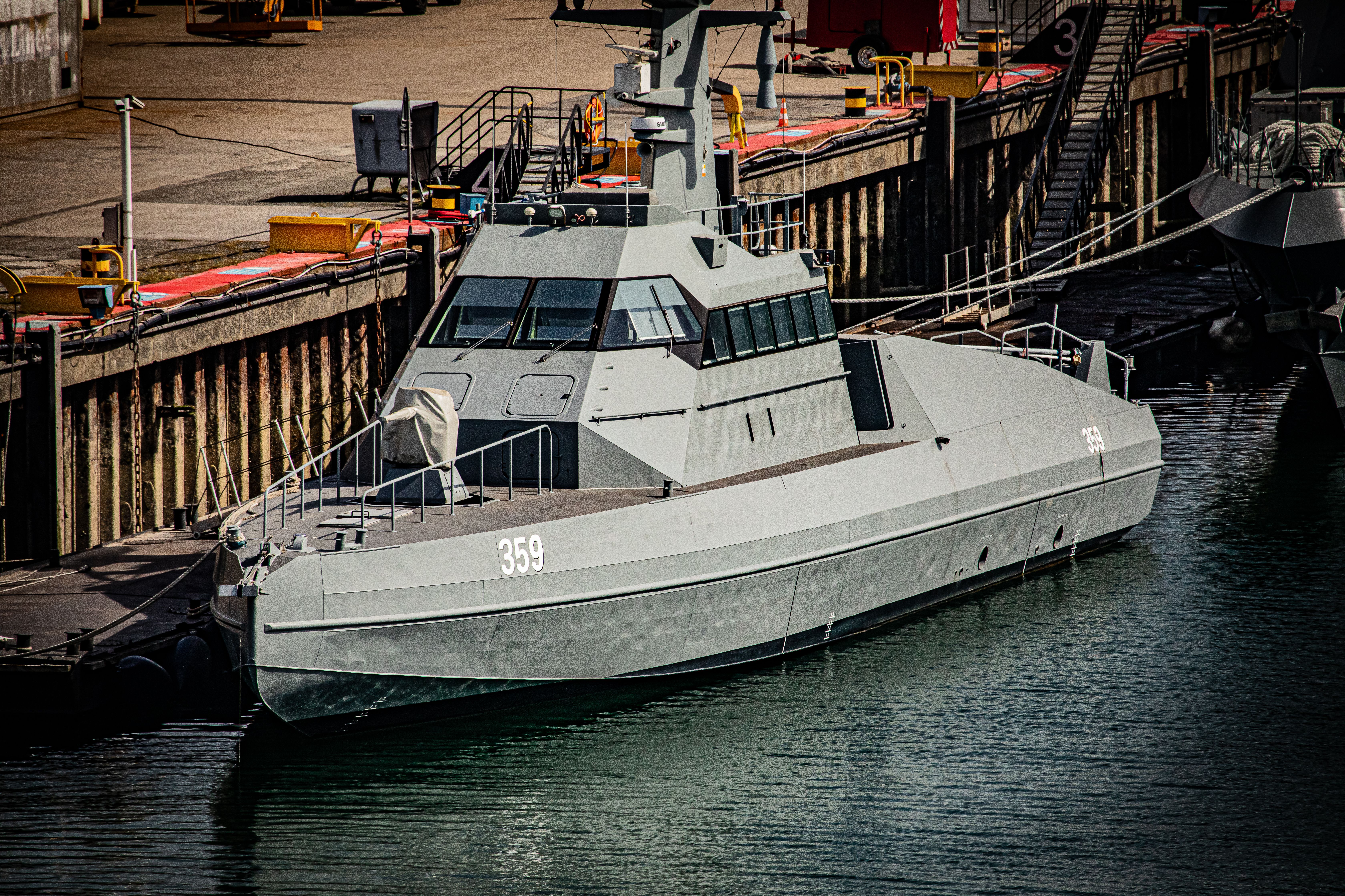 A grey military ship docked in Cherbourg-en-Cotentin, Normandy, reflecting modern naval architecture.