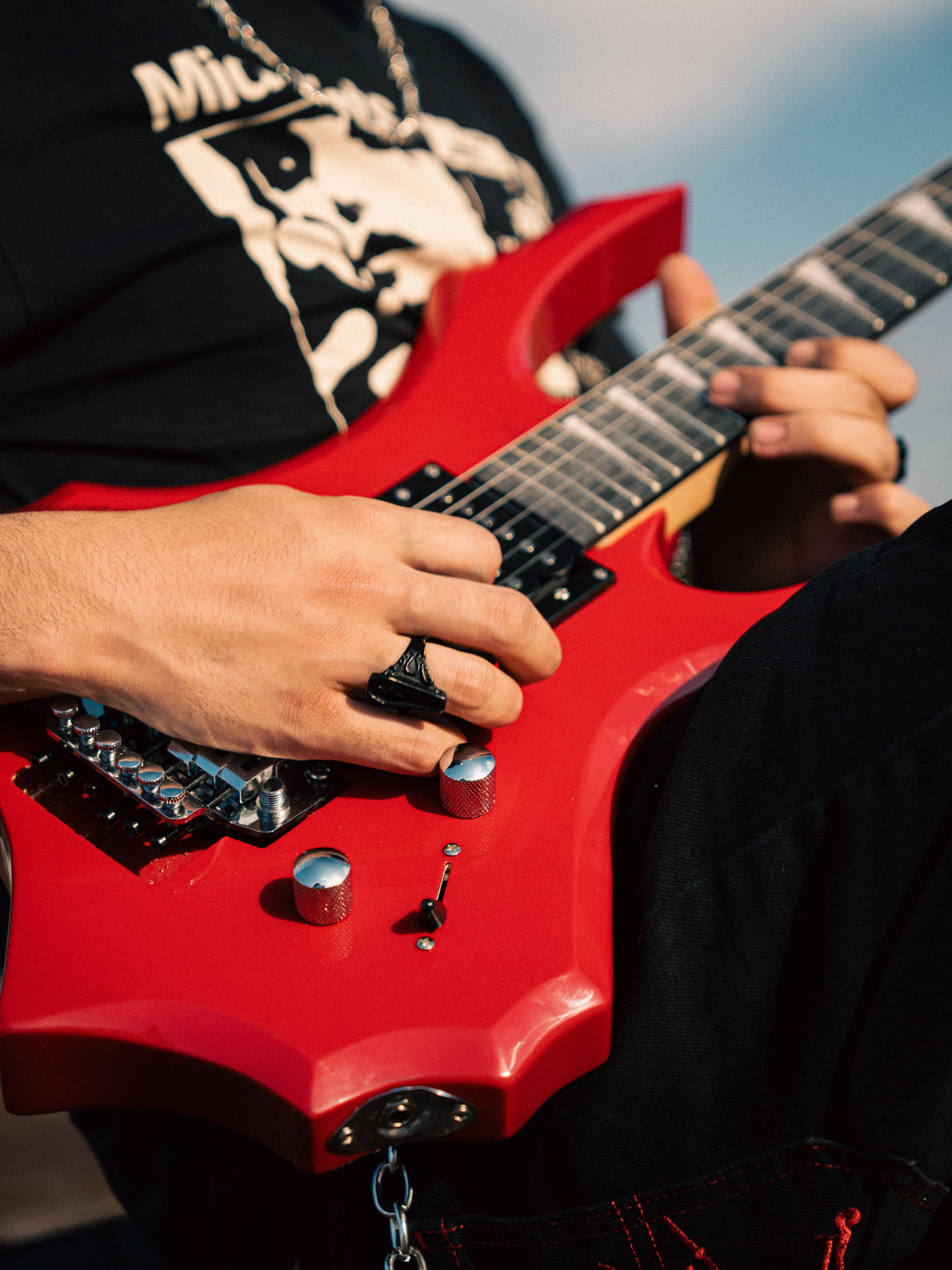Focused view of hands playing a red electric guitar outdoors under sunlight.. pexels, focused, view