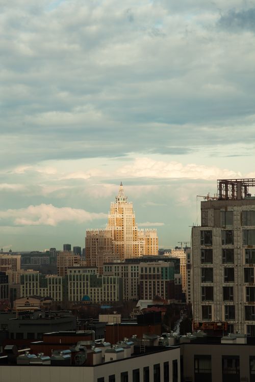 Free A city skyline featuring a prominent historic building under a dramatic cloudy sky at dusk. Stock Photo