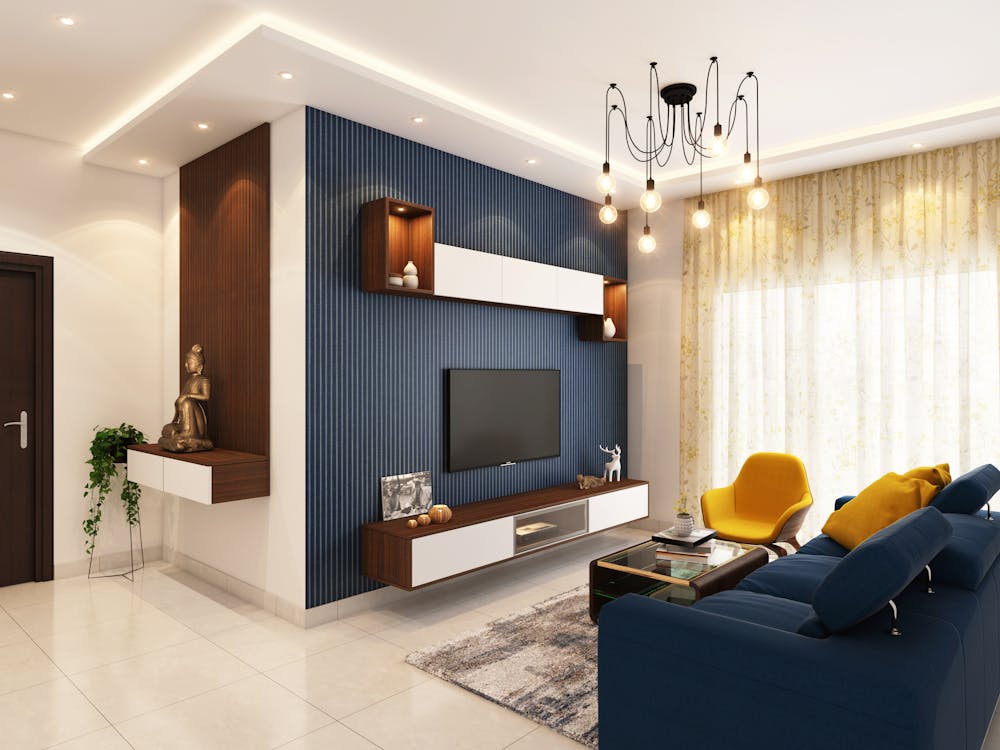 Inside a modern living room with a blue sofa and a yellow chair facing a widescreen TV.