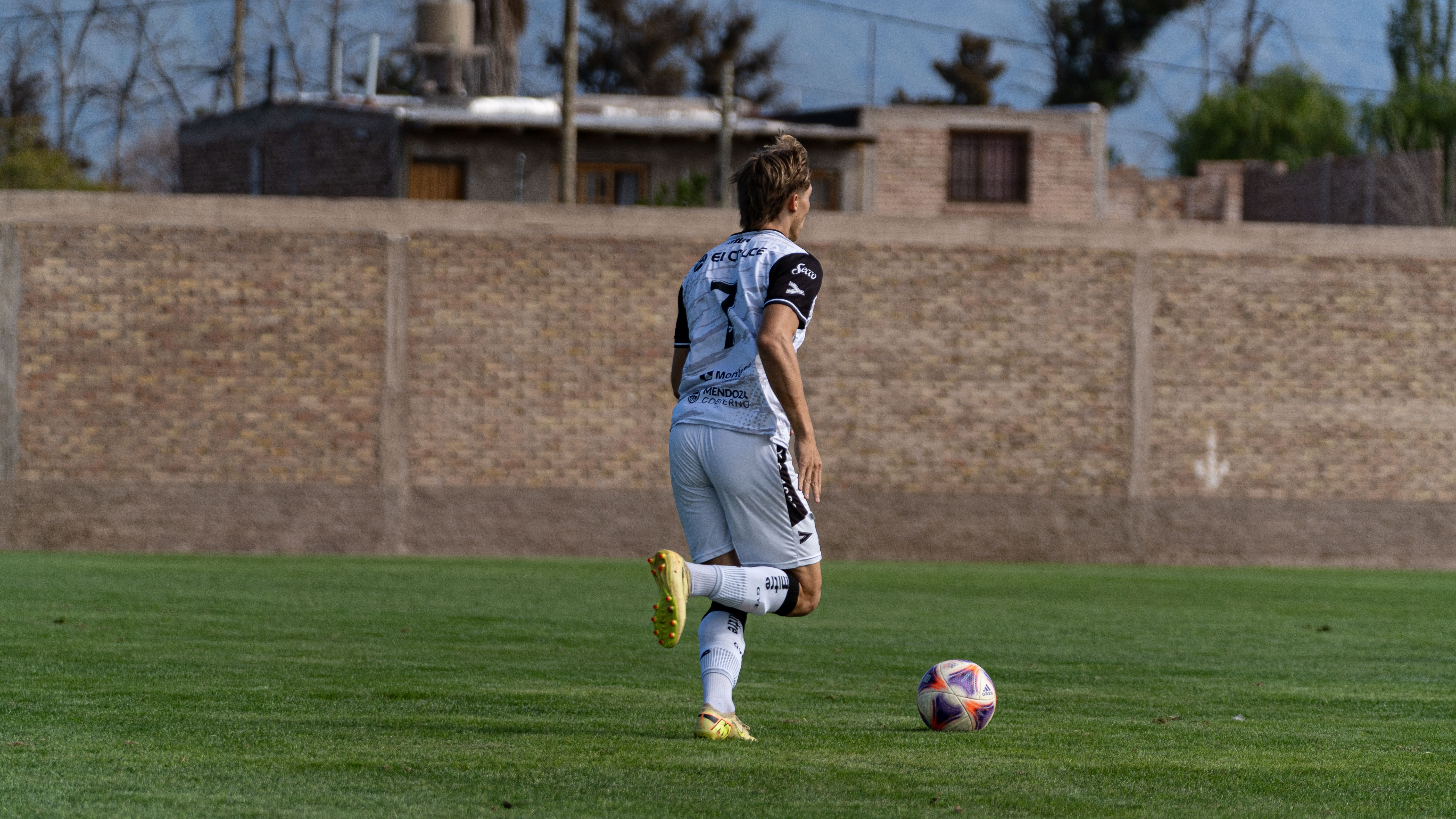 Soccer player in action on a grass field during the day, preparing for a kick.