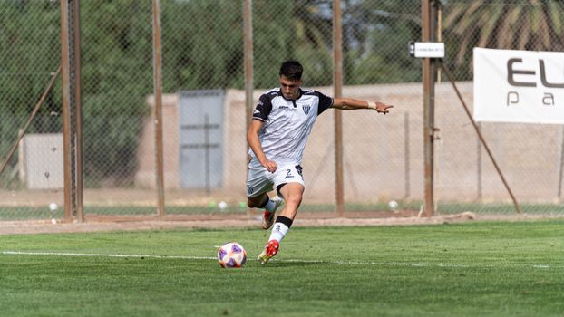 Focused soccer player in action kicking the ball on a sunny outdoor field.