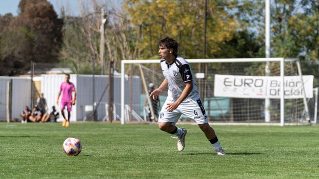 A soccer player in action dribbling the ball during a daytime match, showcasing athletic skills.
