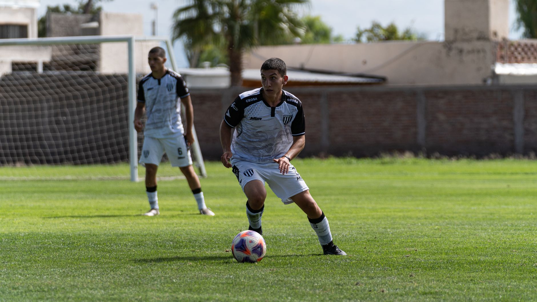 Two young male soccer players in action on a sunny day in a backyard field.