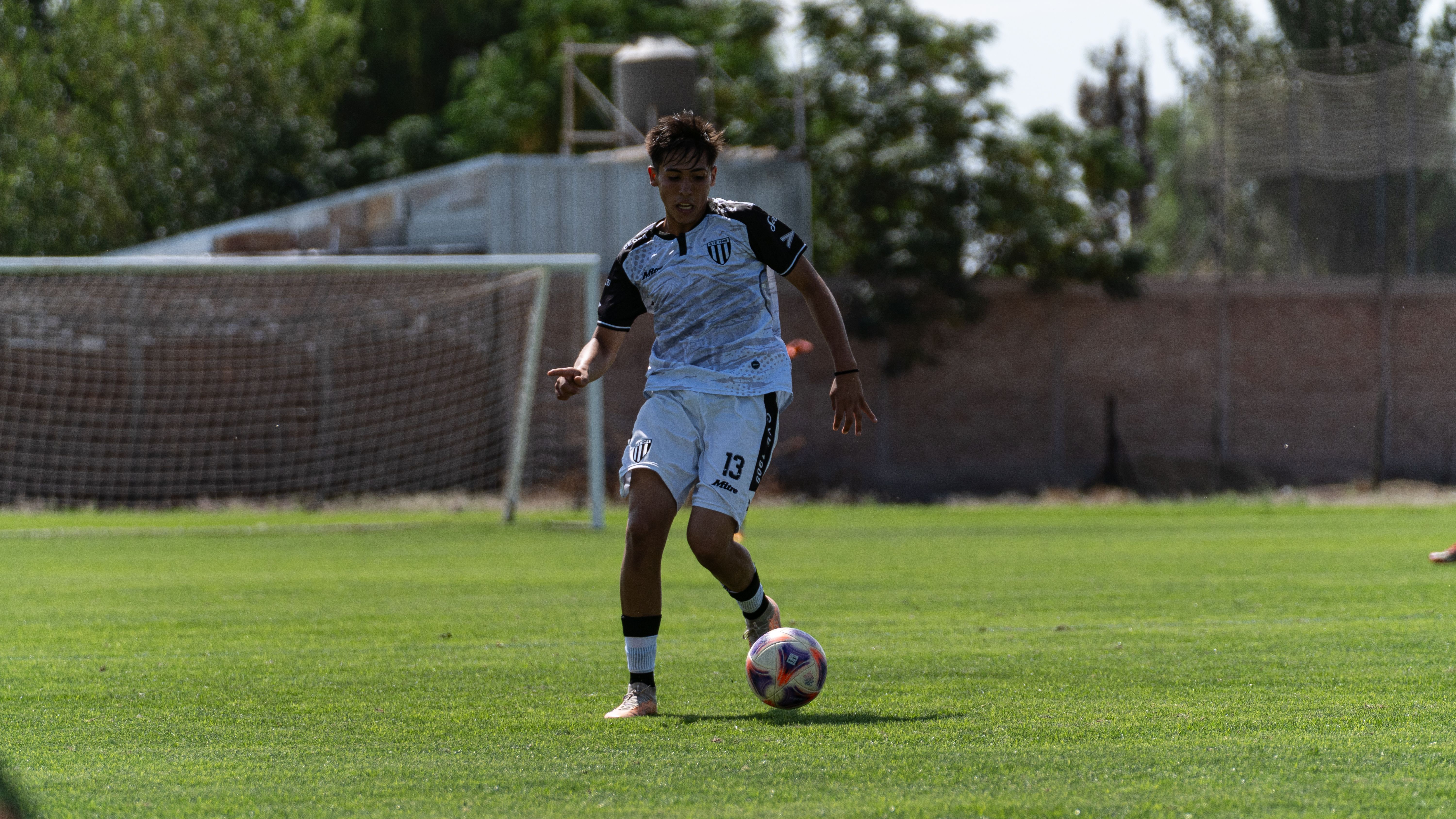 Teenager playing soccer on sunny field