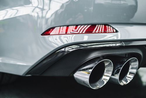 Free Detailed view of a car's exhaust pipes and rear taillight with reflections. Stock Photo