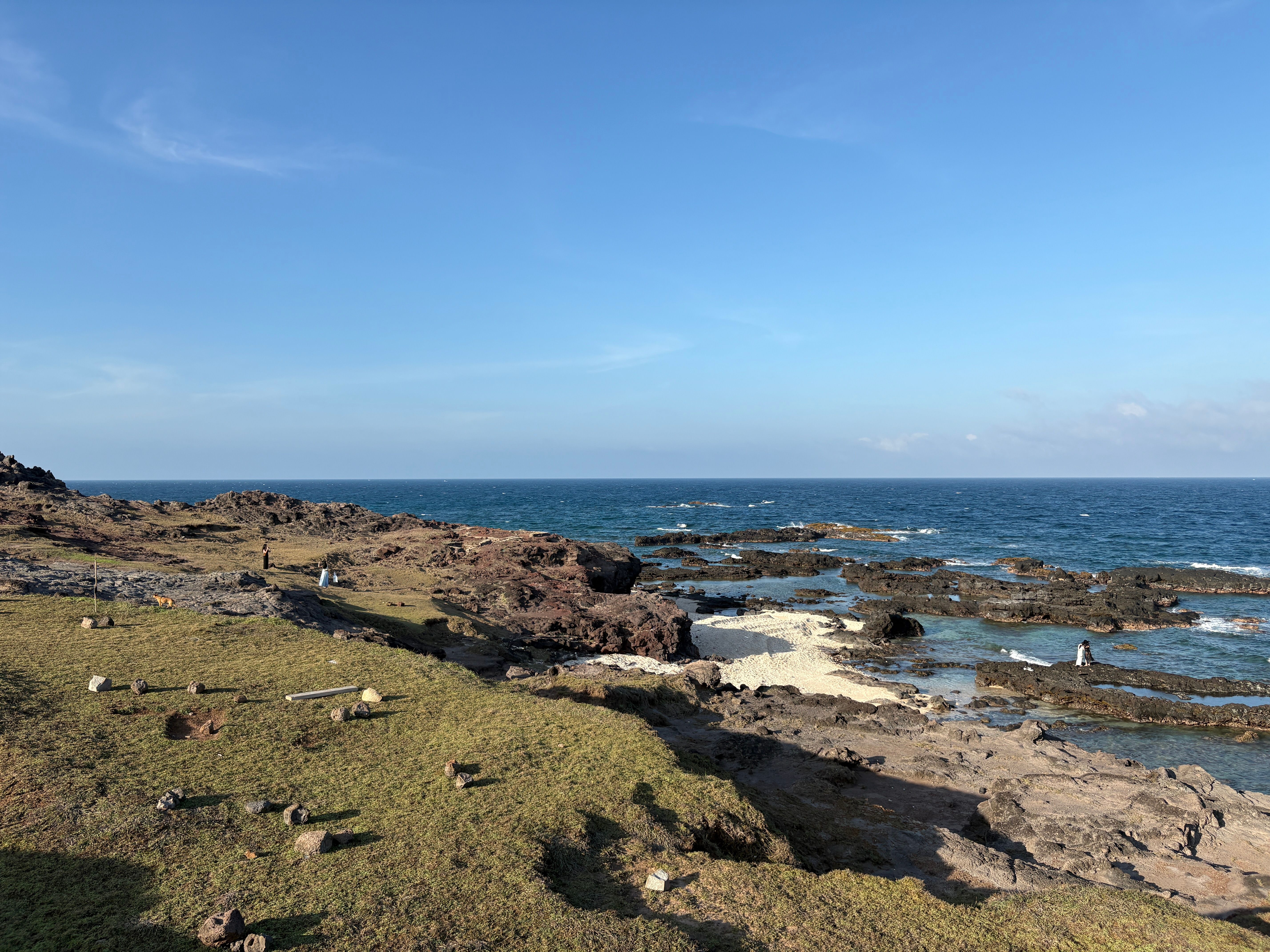 Breathtaking view of a rocky seashore under a clear blue sky, ideal for travel and nature photography.