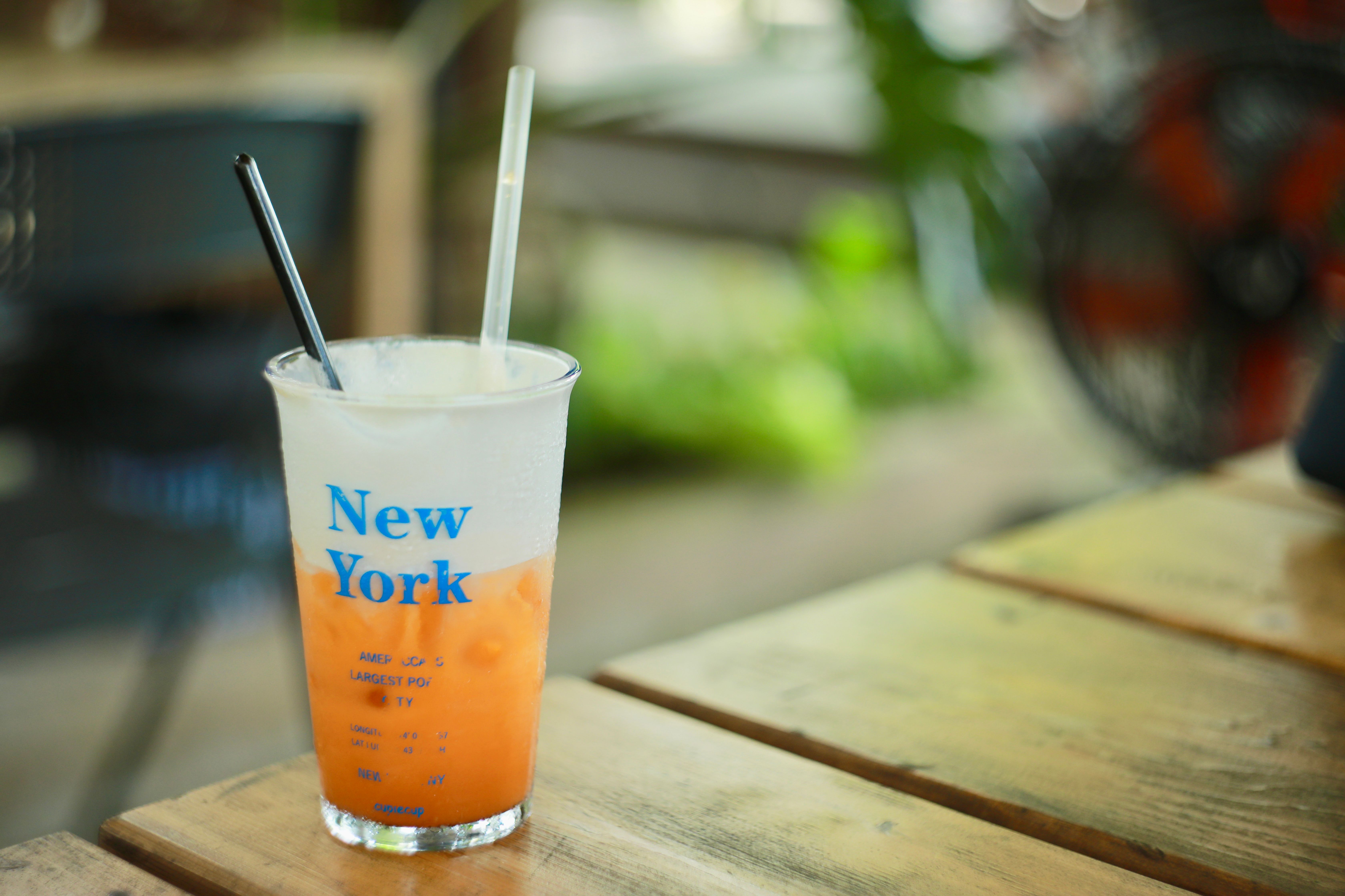 Iced drink in transparent cup with New York text on wooden table