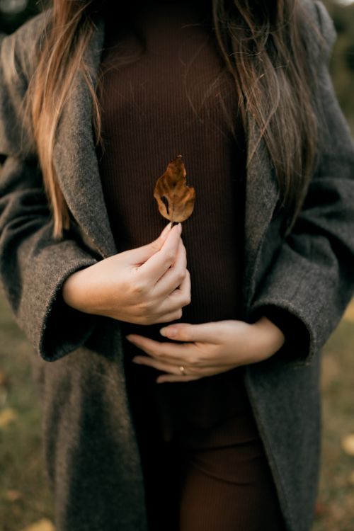 Free Close-up of a woman holding a dry leaf, embodying an autumn theme with muted tones. Stock Photo