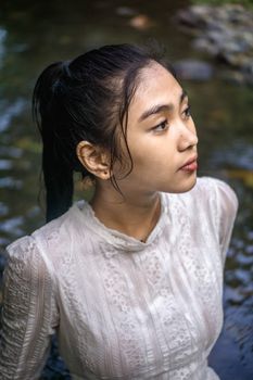 一位穿着白色蕾丝上衣的体贴女人，站在溪流中