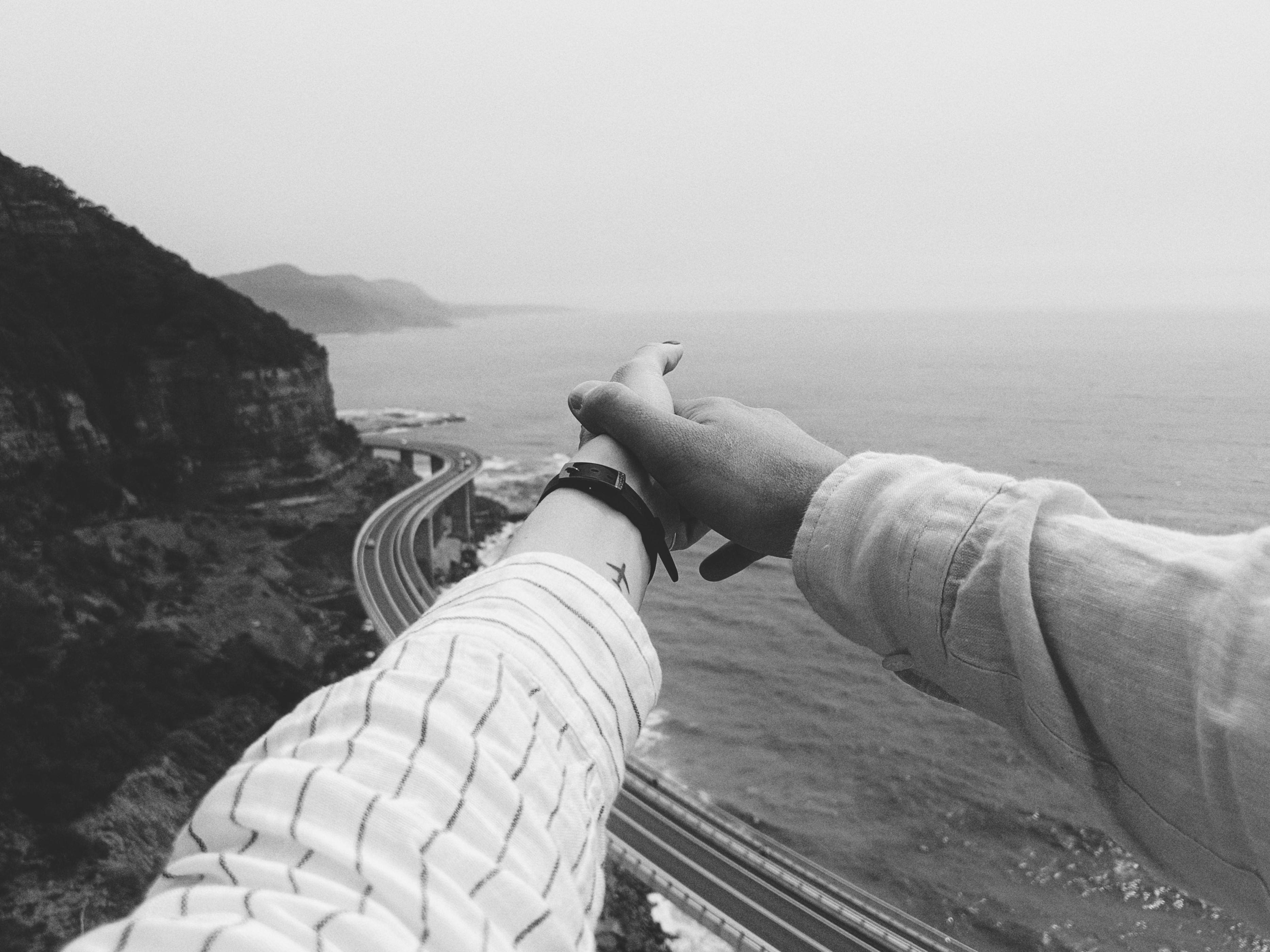 一张浪漫的黑白照片中，双手握着澳大利亚的海洋和风景秀丽的道路