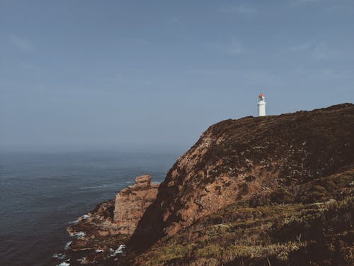 Free Photo of Lighthouse on Cliff Near Body of Water Stock Photo