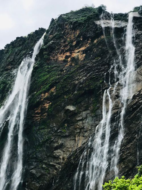 Free Breathtaking view of cascading waterfalls over a rocky mountain cliff, showcasing nature's beauty. Stock Photo