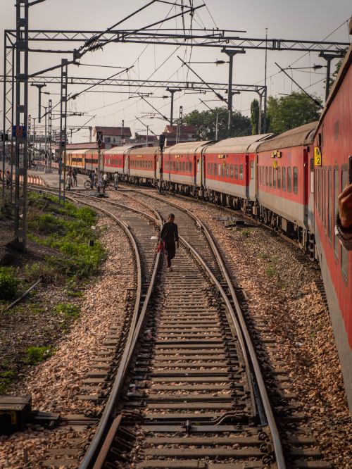 Free A train approaches a station with a person walking along the tracks, highlighting travel and transit. Stock Photo