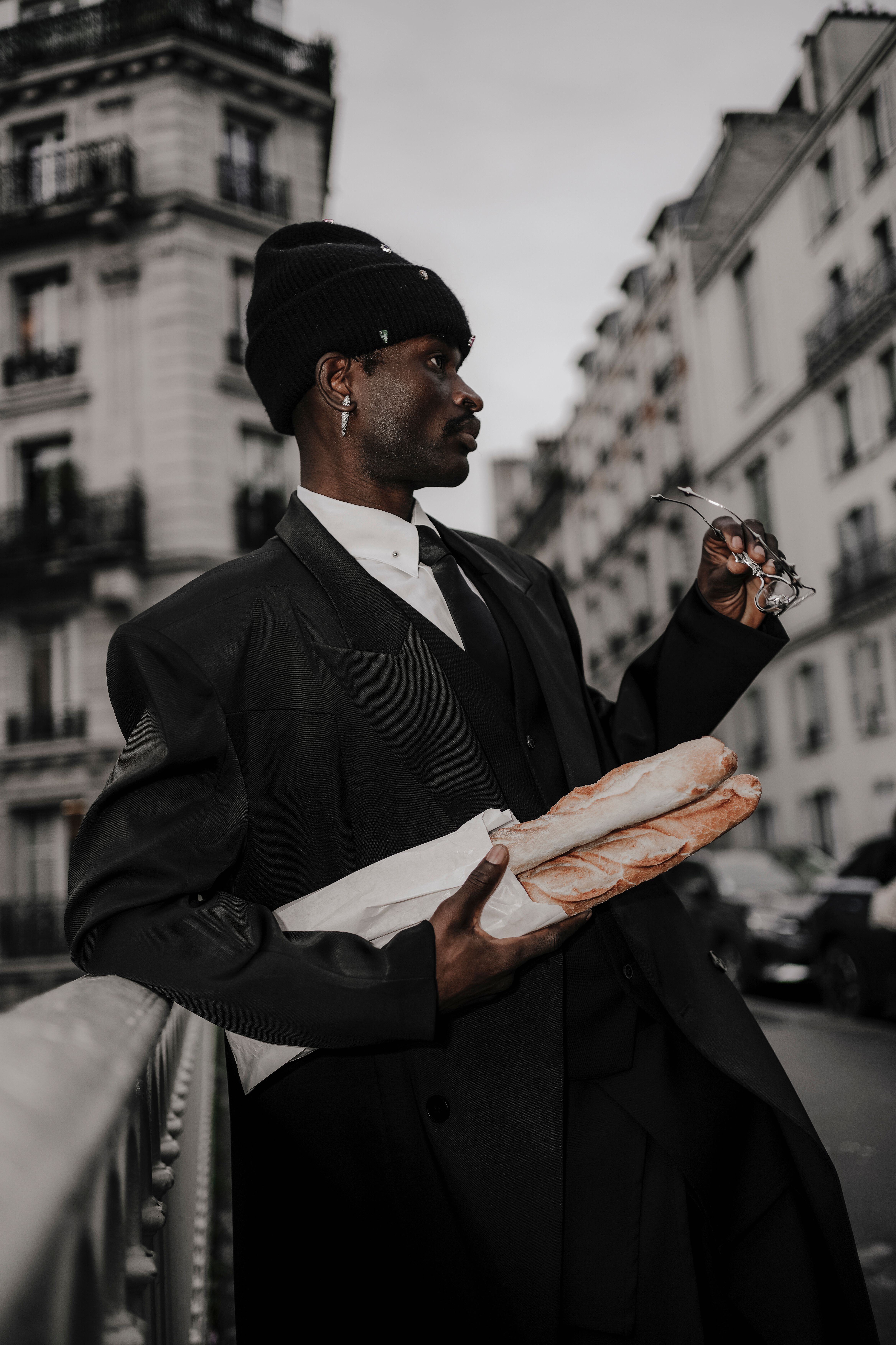 Stylish man in a suit with baguette on a Paris street, embodying urban elegance.