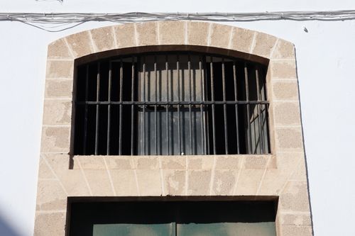 Free Close-up of a rustic window with iron bars on a historic building facade in El Puerto de Santa María, Spain. Stock Photo