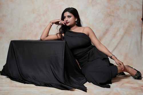 Free A glamorous woman in an elegant black dress poses indoors, exuding confidence and style. Stock Photo