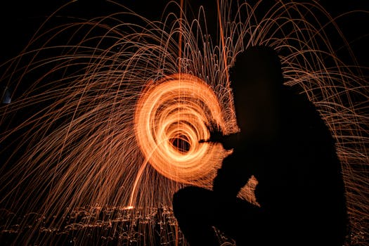 Mesmerizing long exposure photo of spinning sparks creating a light painting silhouette effect.