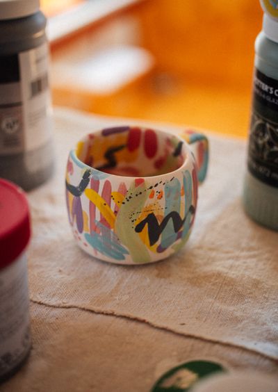 Hand-painted ceramic mug with bright glaze and paint bottles — photo by Raymond Petrik on Pexels