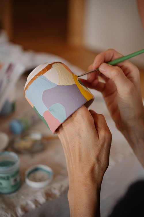 Free Close-up of a person painting a ceramic pot in various pastel colors, showcasing creative expression. Stock Photo
