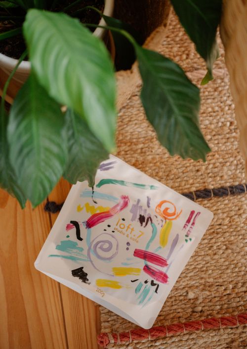 Free A vibrant abstract art print on a wooden surface beside a green plant. Stock Photo