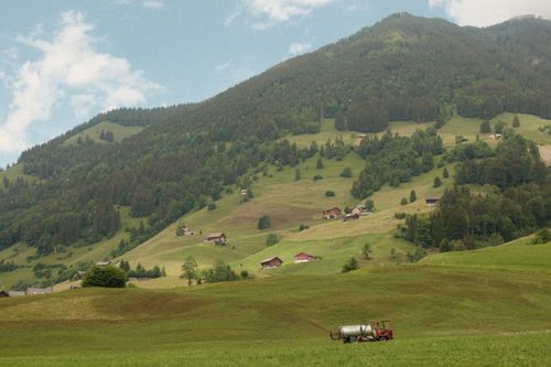 Free Scenic view of lush green hills with farm tractor in Wolfenschiessen, Switzerland. Stock Photo
