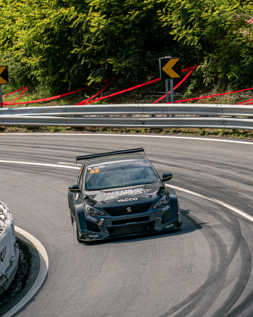 Free A sleek race car navigates a sharp mountain curve during a daytime race event. Stock Photo