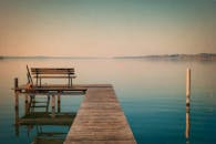 黄昏时分，宁静的湖面上延伸着木制码头上的长凳，构成一片适合放松的宁静风景