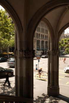 A view through stone arches onto a busy street in Zurich, Switzerland, featuring blurred cyclists and cars.