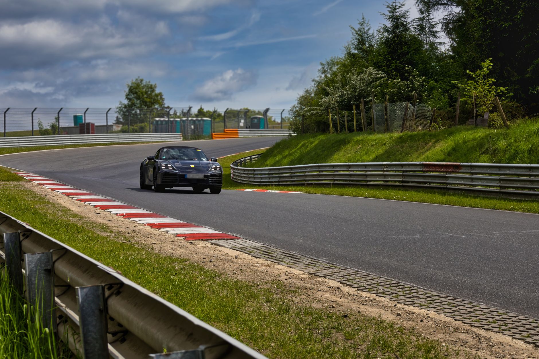 A sleek sports car races around the Nürburgring Nordschleife, capturing the thrill of motorsport.