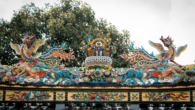 Intricate Asian temple roof adorned with colorful dragon sculptures.