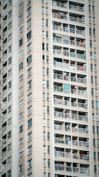 A tall urban residential building with multiple balconies in a city setting.