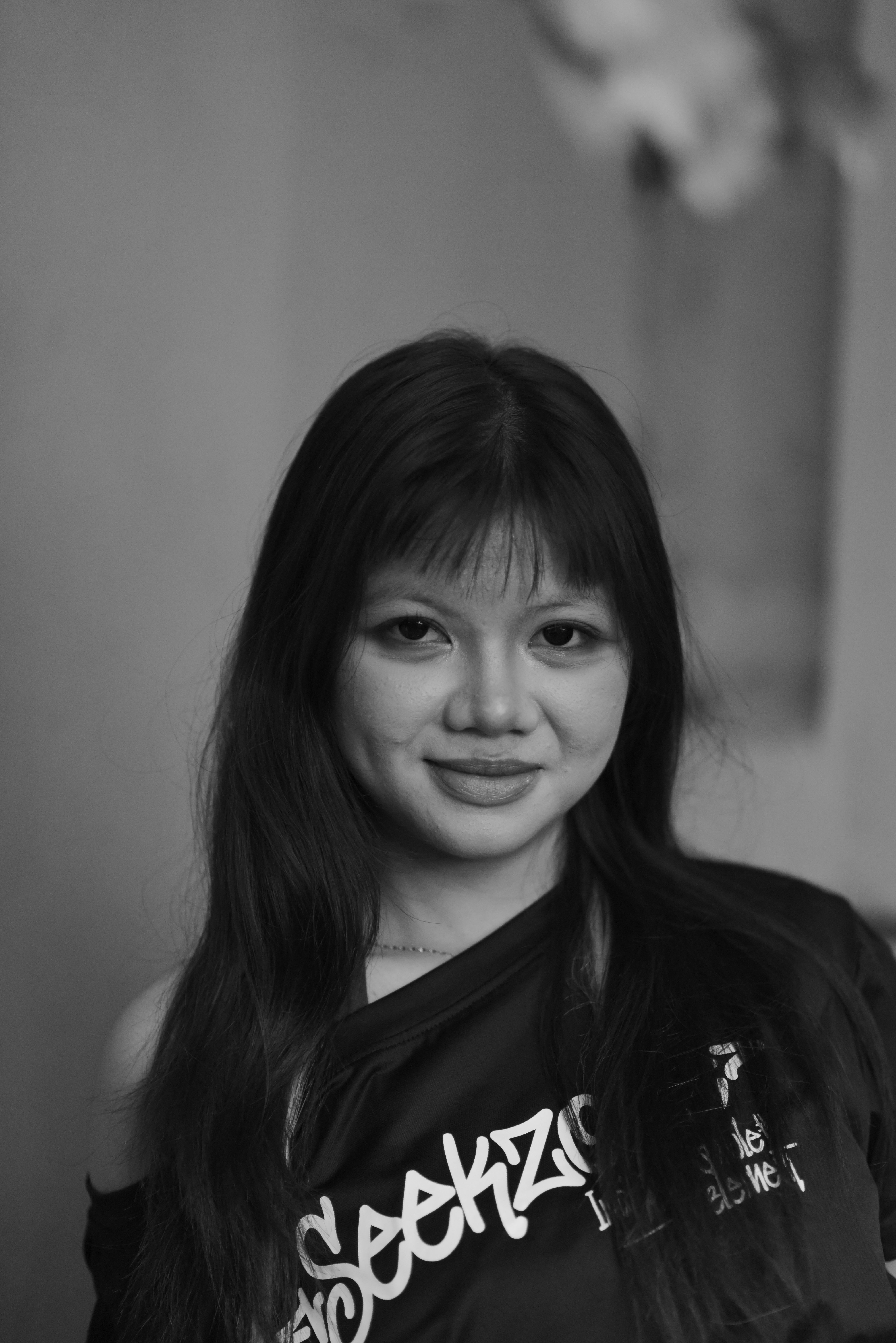Black and white portrait of a young woman smiling softly indoors.
