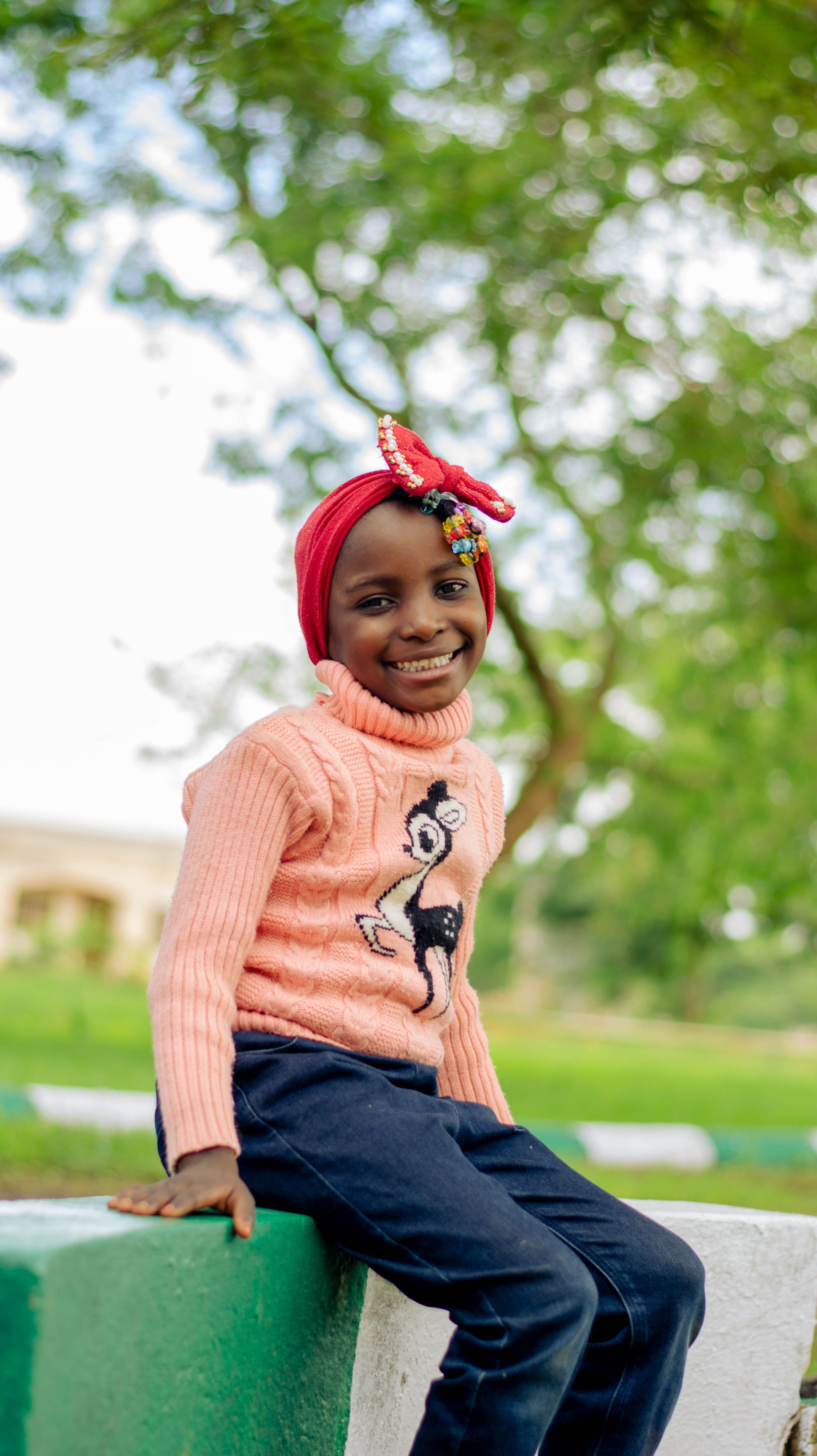 Cheerful child posing outdoors in colorful attire during the day.