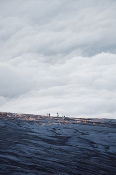 Hikers explore the vast rocky terrain of Mount Kinabalu under a dramatic cloudy sky in Sabah, Malaysia.