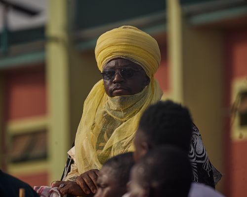 Free Man in yellow turban and traditional attire at outdoor event. Stock Photo