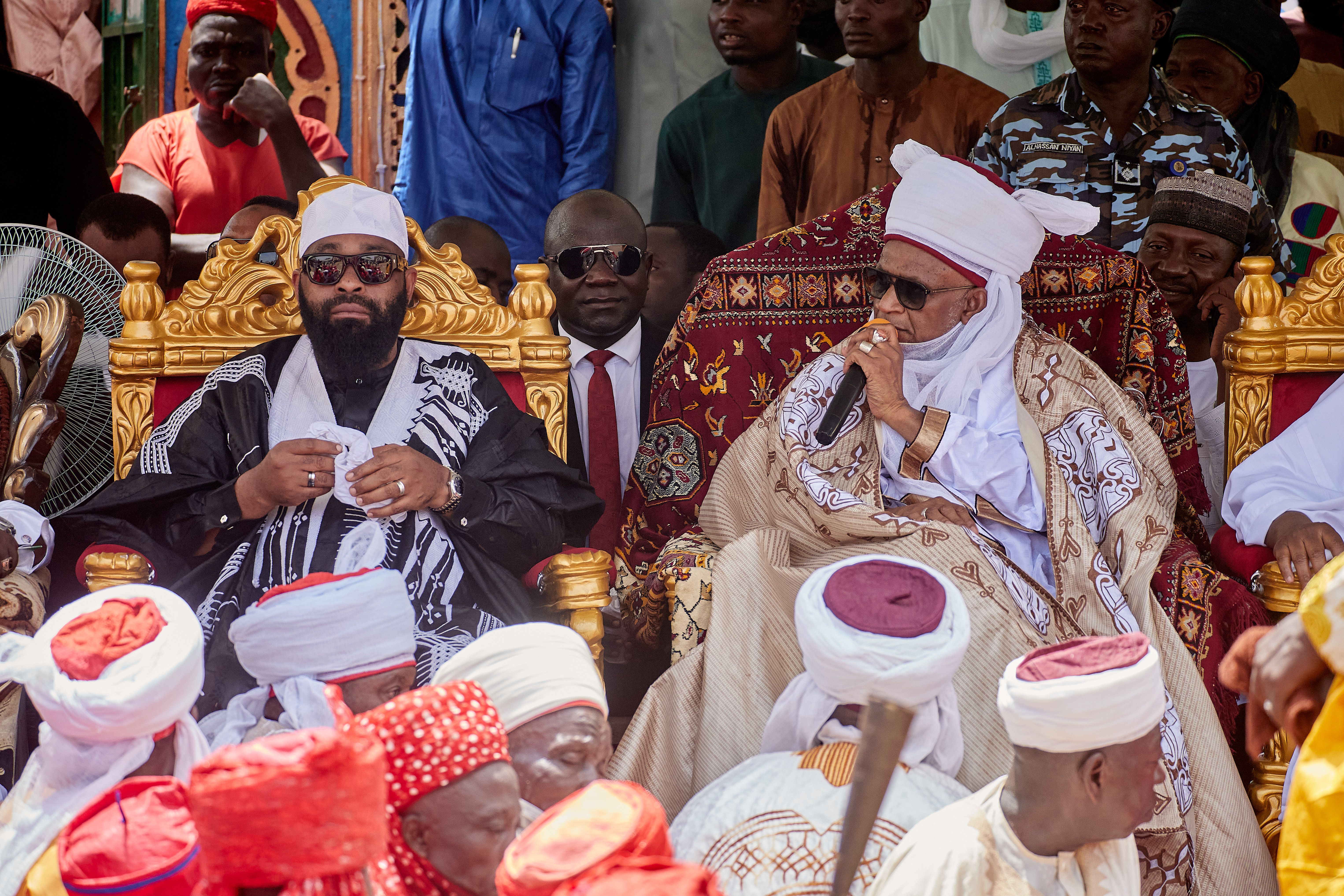 African traditional leaders in ceremonial attire at a cultural gathering outdoors.