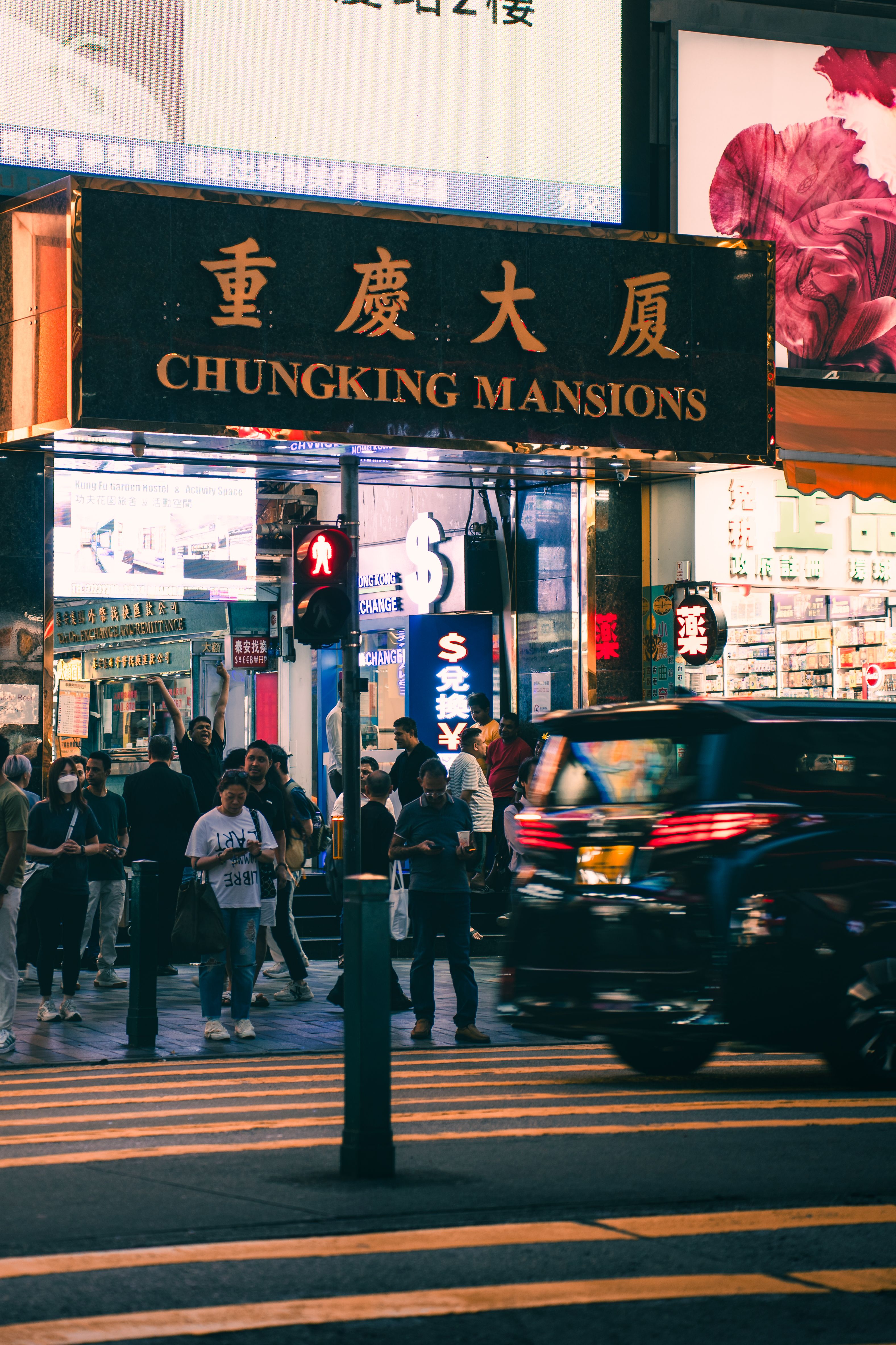 Night street view of bustling crowds and traffic at Chungking Mansions in Hong Kong.