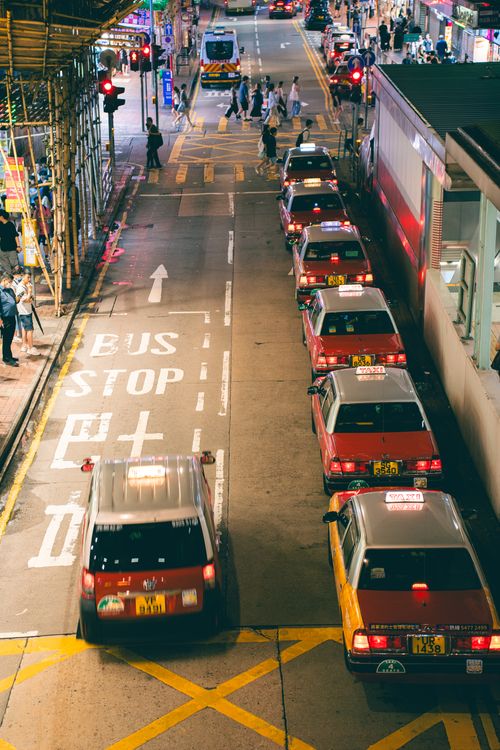Free Urban night scene with taxis lined on a city street beside a marked bus stop. Stock Photo