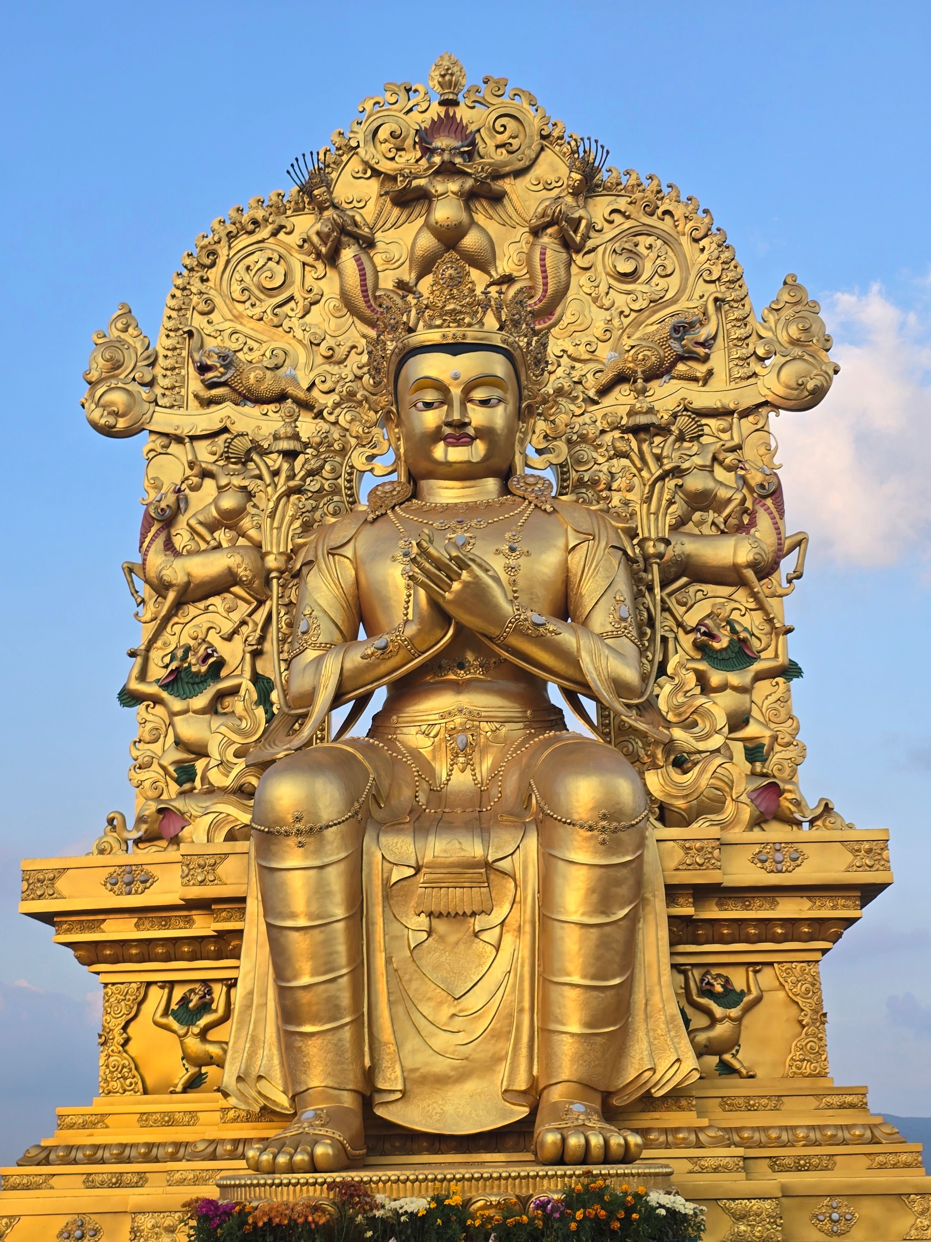 Majestic golden Buddha statue with intricate detailing against a clear blue sky.