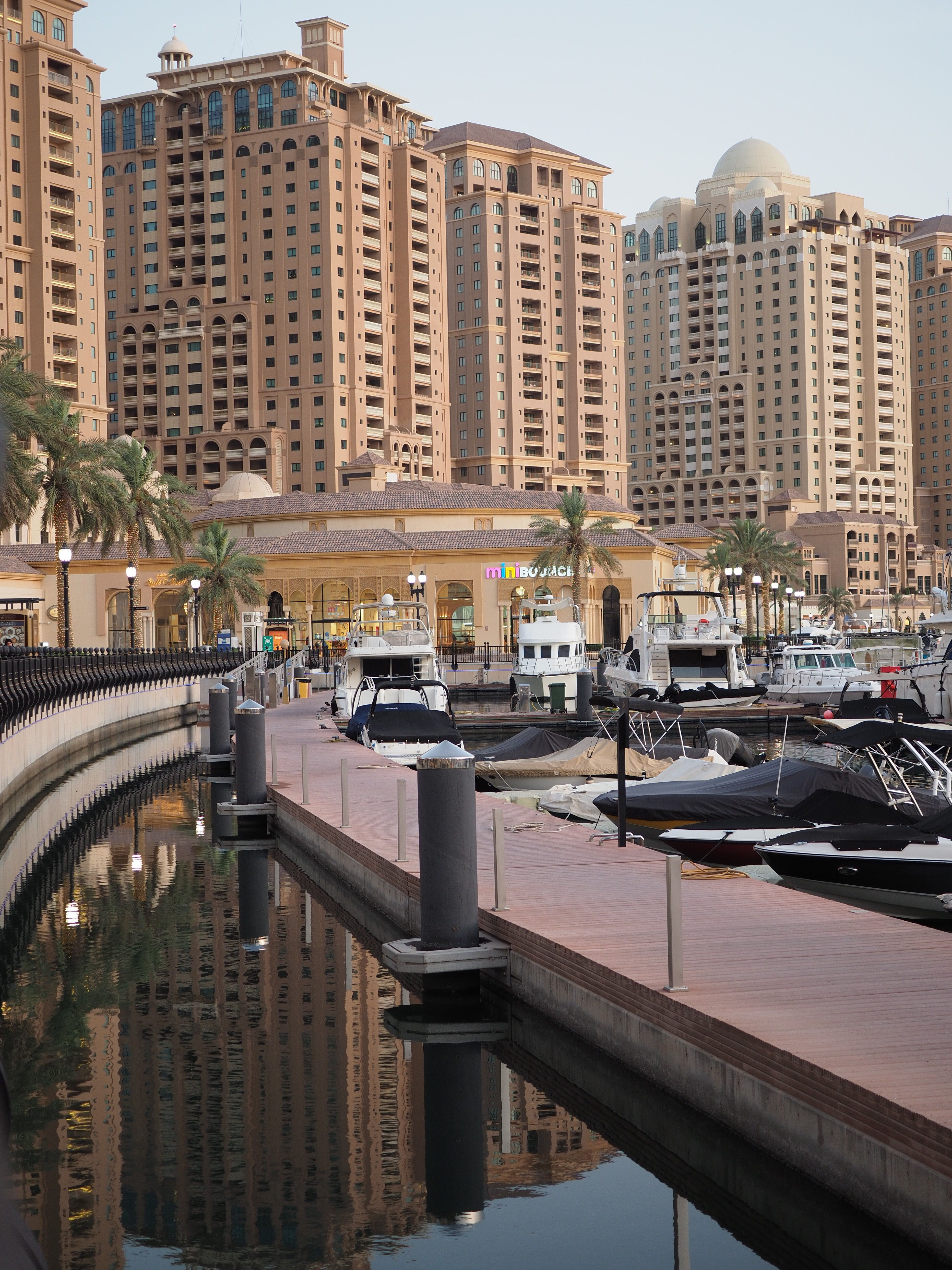 Experience the tranquil luxury of a marina in Doha with stunning architecture in the backdrop.